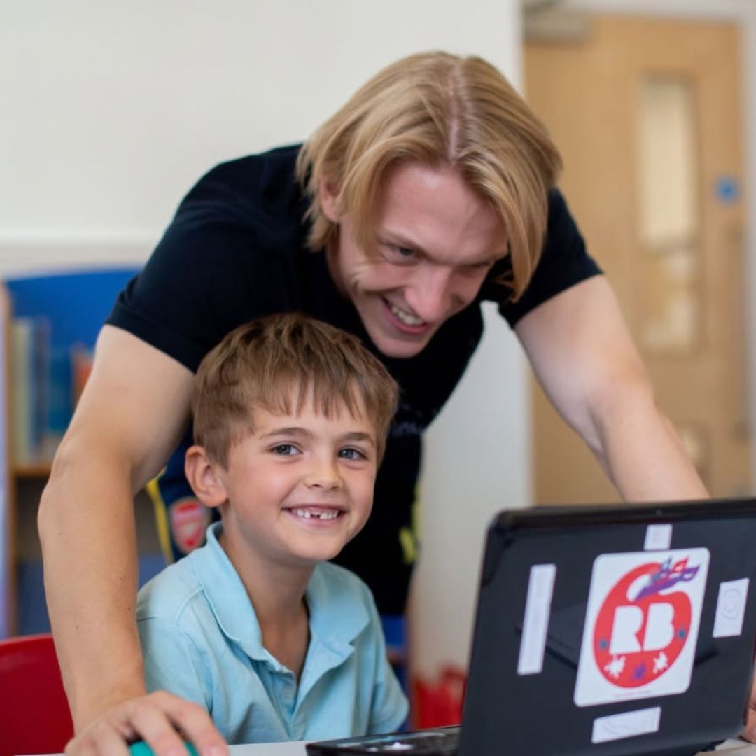 Teacher supporting coding camp student